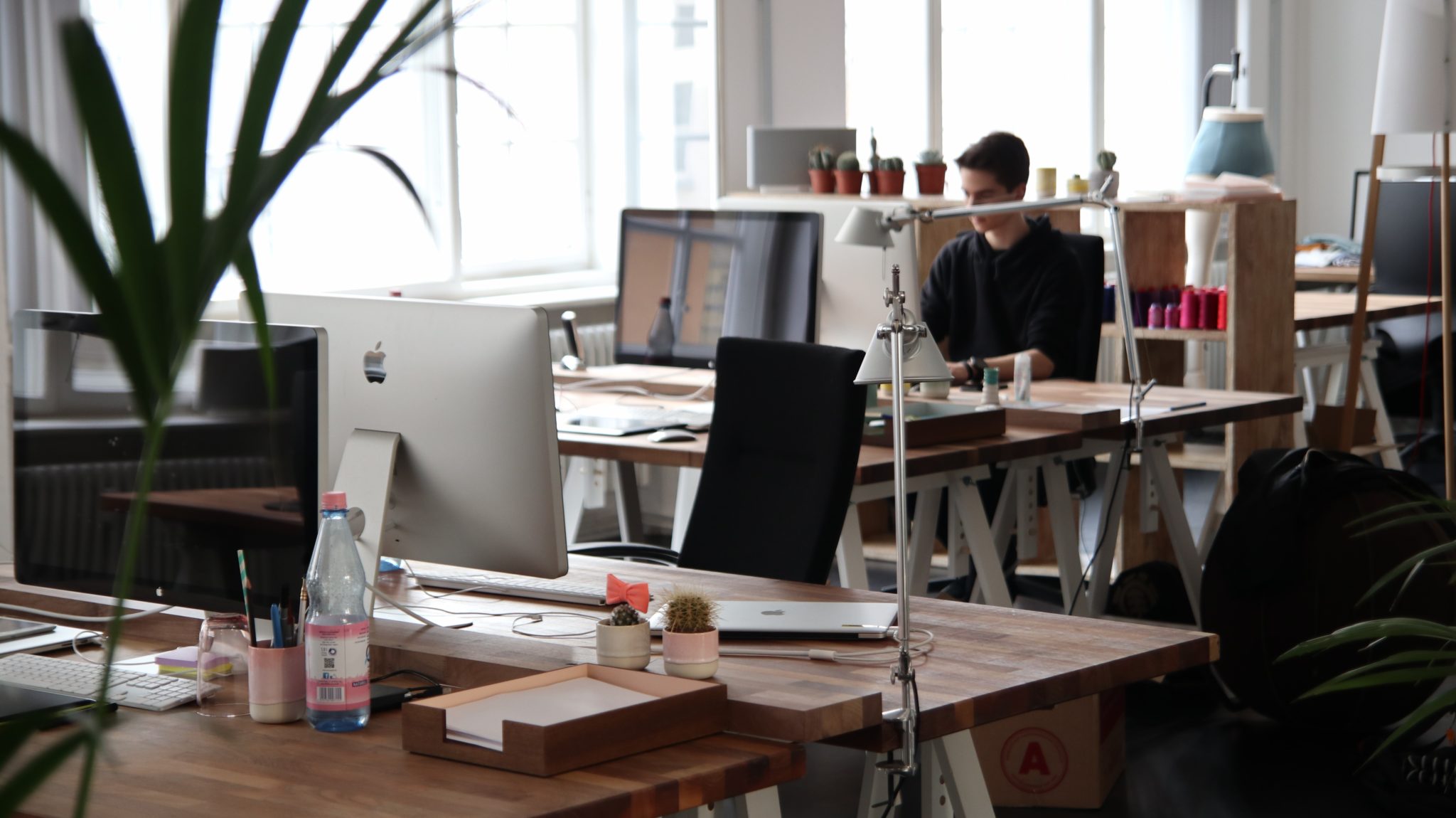 Modern office workspace with iMac monitors and a person working at a back desk