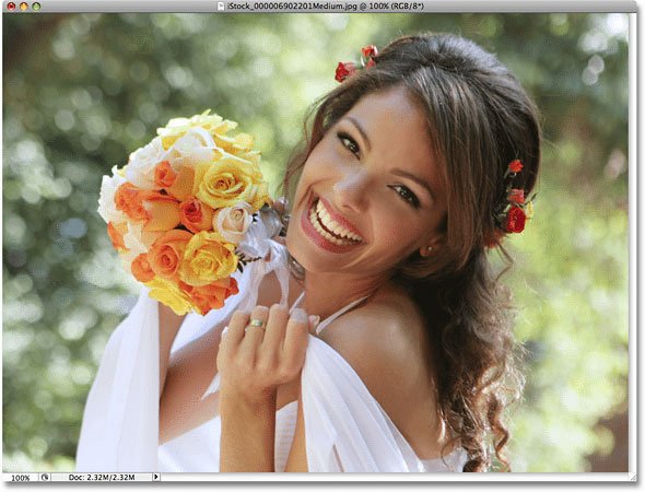Smiling bride holding a yellow and orange rose bouquet shown in a Photoshop window