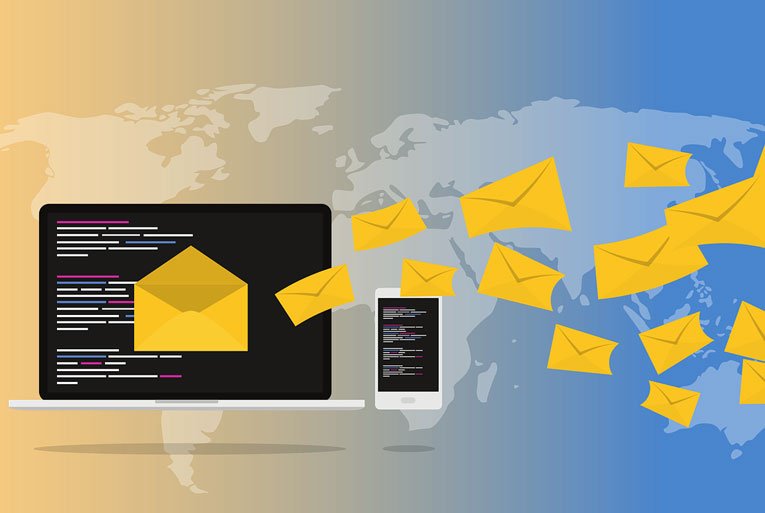 Laptop and phone with yellow envelopes flying out over a world map