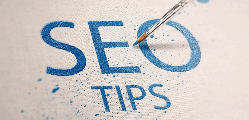 SEO Tips painted in blue letters on canvas with paintbrush and splatters