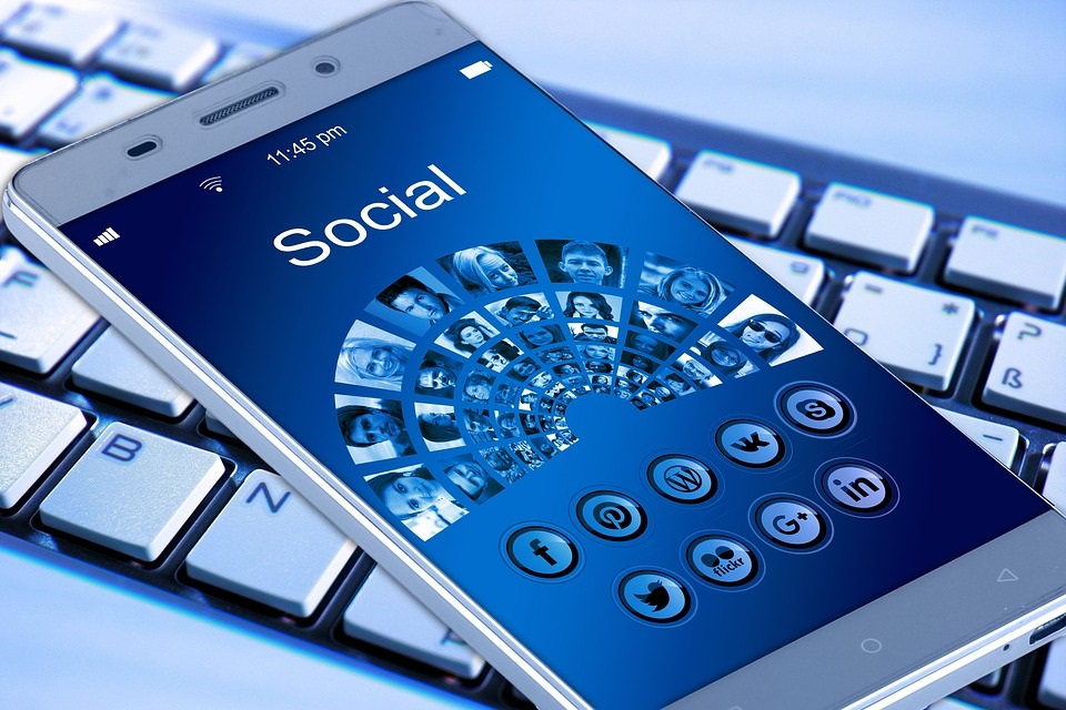Smartphone screen showing social network profile icons resting on a keyboard