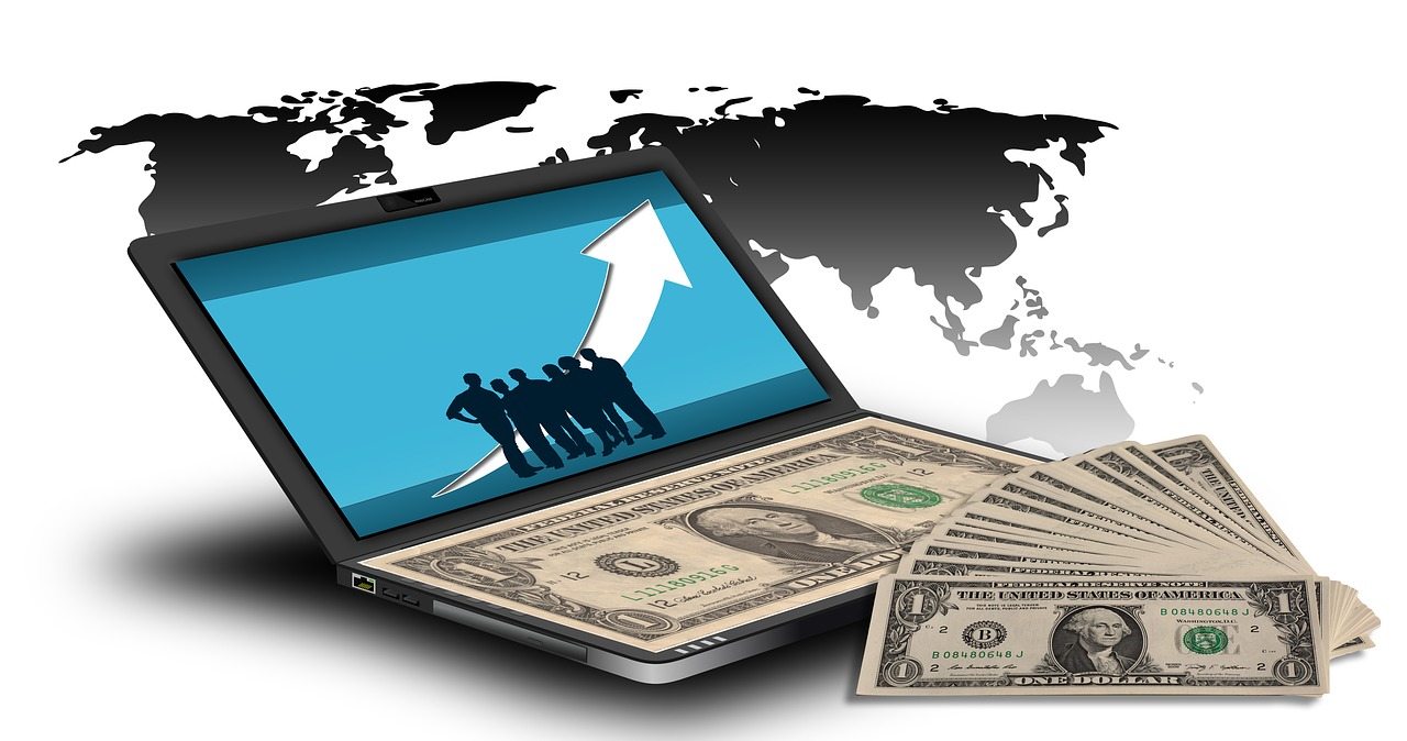 Laptop with rising arrow and team silhouettes beside a fan of one dollar bills and world map